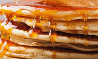 a stack of pancakes with syrup dripping down the sides