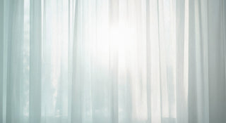 a sunny day with the shear blue tinted curtains that are closed