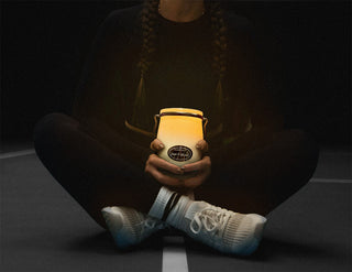 a person sitting cross legged holding a 22oz candle black backgound