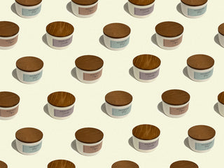 multiple statement collection cream jars with their wood lids on a pale yellow background