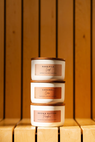 a three stack of the fall statement candles on a wood bench 