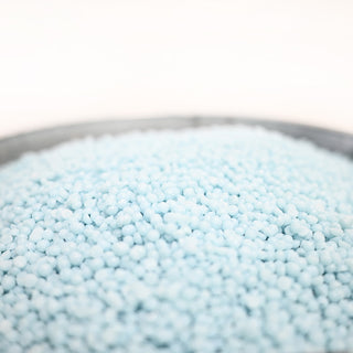 Close-up of light blue wax beads in a bowl with a blurred background