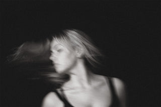 woman flipping her hair with her eyes closed black background 
