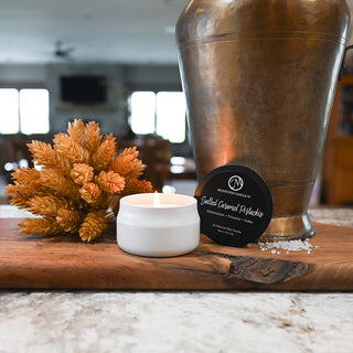 Candle, decorative vase, and small plant on a wooden surface with a blurred indoor background.