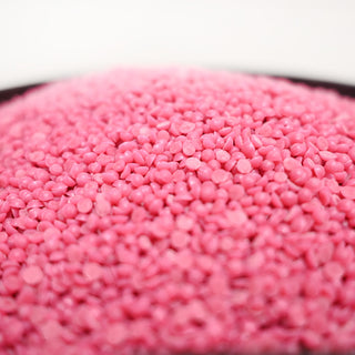 Close-up of pink wax beads in a bowl