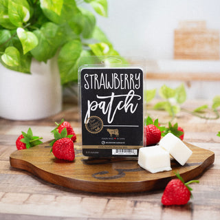 Wax melt package labeled 'Strawberry Patch' on a wooden board with strawberries and wax cubes
