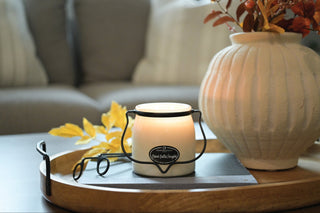 Candle and vase on a wooden tray with a blurred sofa in the background