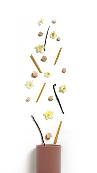 vanilla bean wood bits flowers and sandlewood coming out of a rosewood jar 