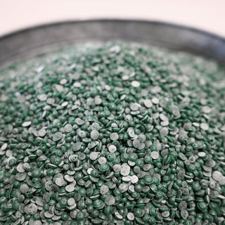 Close-up of green scented wax beads in a metal container
