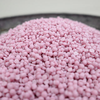 Close-up of pink wax beads on a white background
