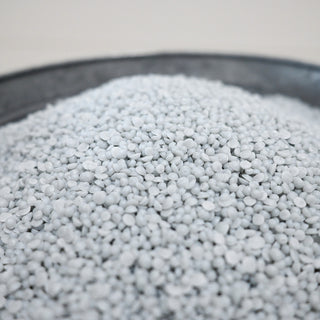 Close-up of light gray scented wax beads in a container with a blurred background