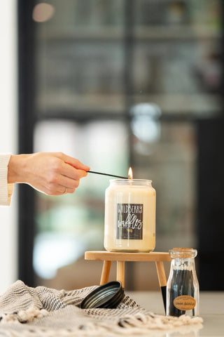 Person lighting a candle with a match, surrounded by decorative items on a table