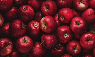 a bushel of apples with water droplets on them 
