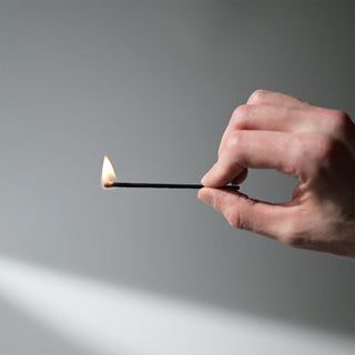 a hand holding a lit match 