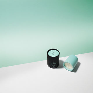 Seafoam green votive candle with holder labeled 'Endless Sea' sitting on a white surface with a seafoam green background