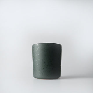 a flecked forest colored tumbler of sandalwood and fir candle   