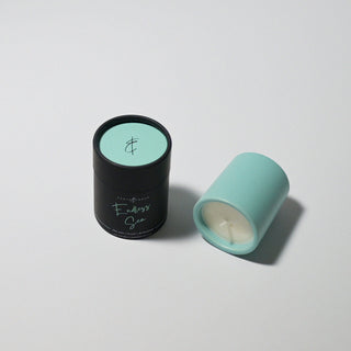 a torquoise votive laying down with its endless sea tube beside it 