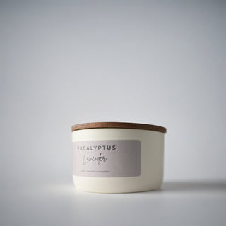 White candle in a tin with a lid on a gray background