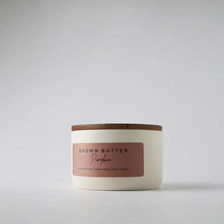 White candle in a tin with a lid on a gray background