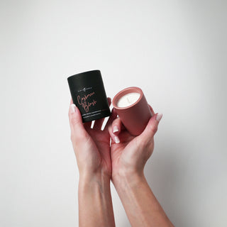 Blush colored ceramic container with candle and holder labeled 'Cashmere Blush' being held against a white background