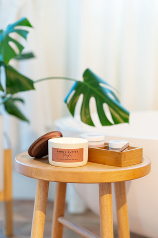 a ceramic statment collection jar in the bathroom on a stool and a monstera plant 