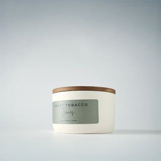 White candle in a tin with a lid on a gray background